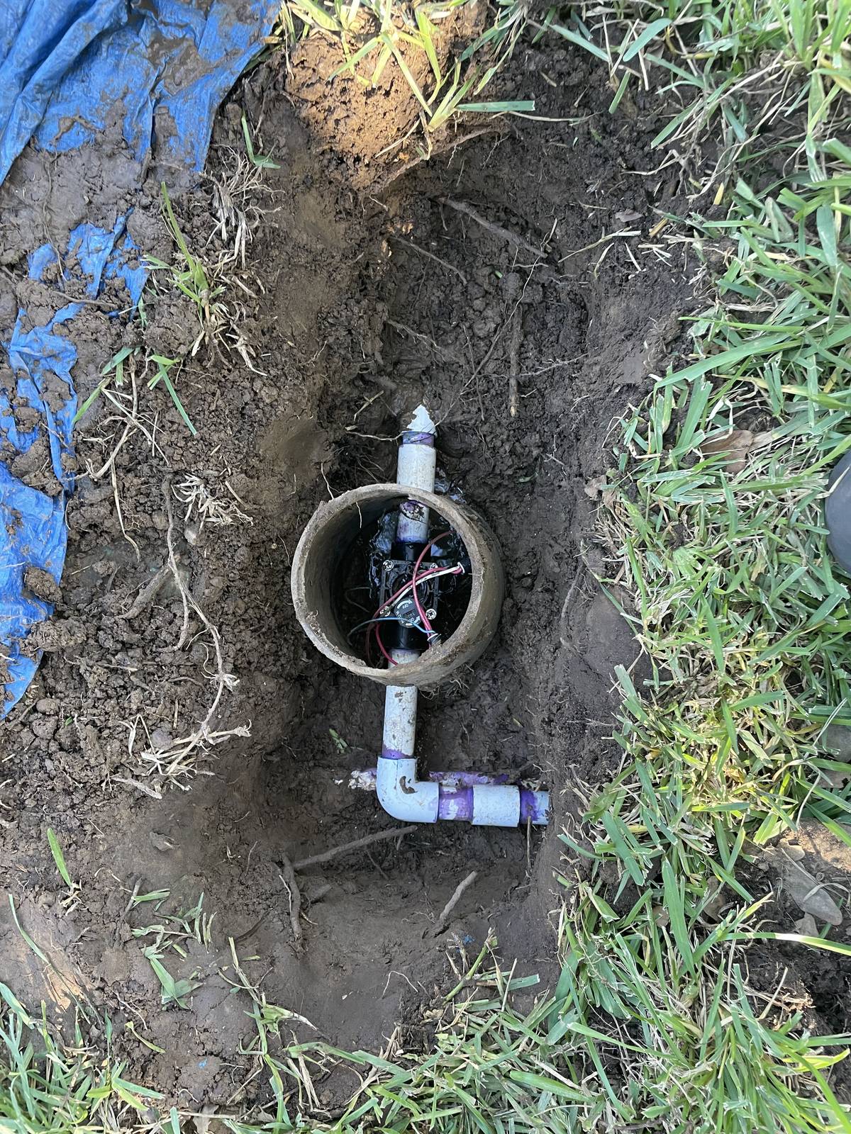 Repaired sprinkler pipe and replaced valve inside a round valve sleeve, dug out in a Keller, Texas yard before backfill